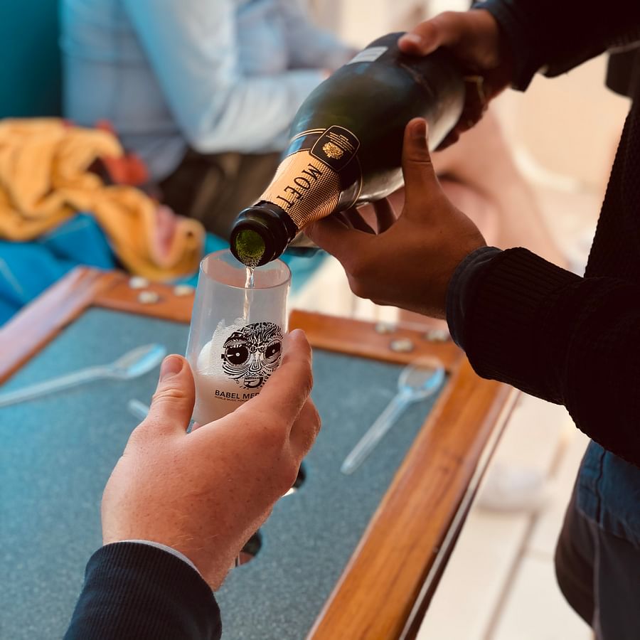 Hand pouring sweet champagne into a tall flute glass